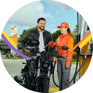 Cliente en motocicleta junto a colaboradora en una Estación de Servicio Primax
